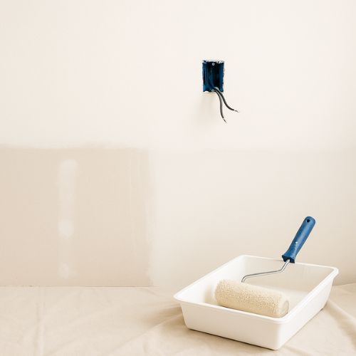 Rouleau de peinture et bac sur un sol protégé lors d’un chantier de rénovation murale.