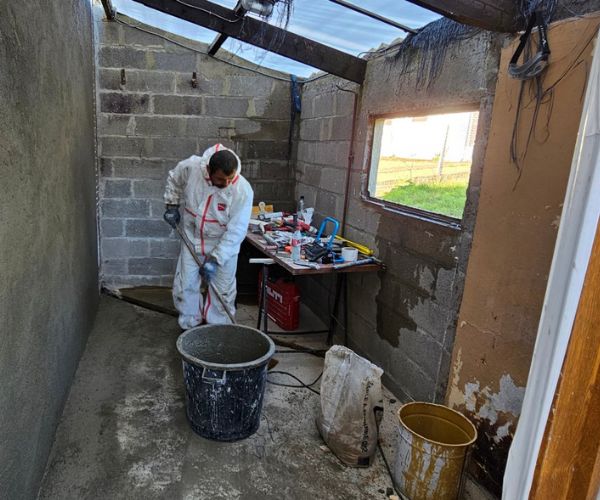 Artisan Batim Travaux préparant un mur en béton pour la rénovation d’une cuisine d’été.