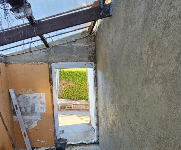 Application d’enduit sur un mur en béton dans le cadre d’une rénovation.