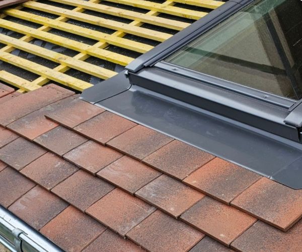 Détail de toiture rénovée avec pose d’une fenêtre de toit moderne.